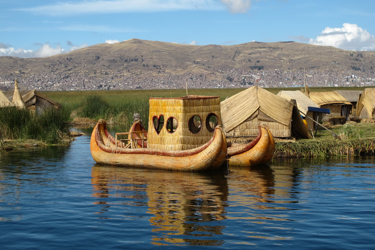 View of Lake Titicaca with traditional reed boats and the Andes in the background