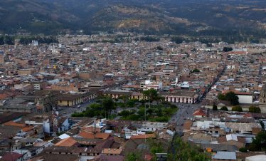 Panoramic view of Cajamarca, Peru, showing the city's colonial architecture, the central plaza, and surrounding mountains.