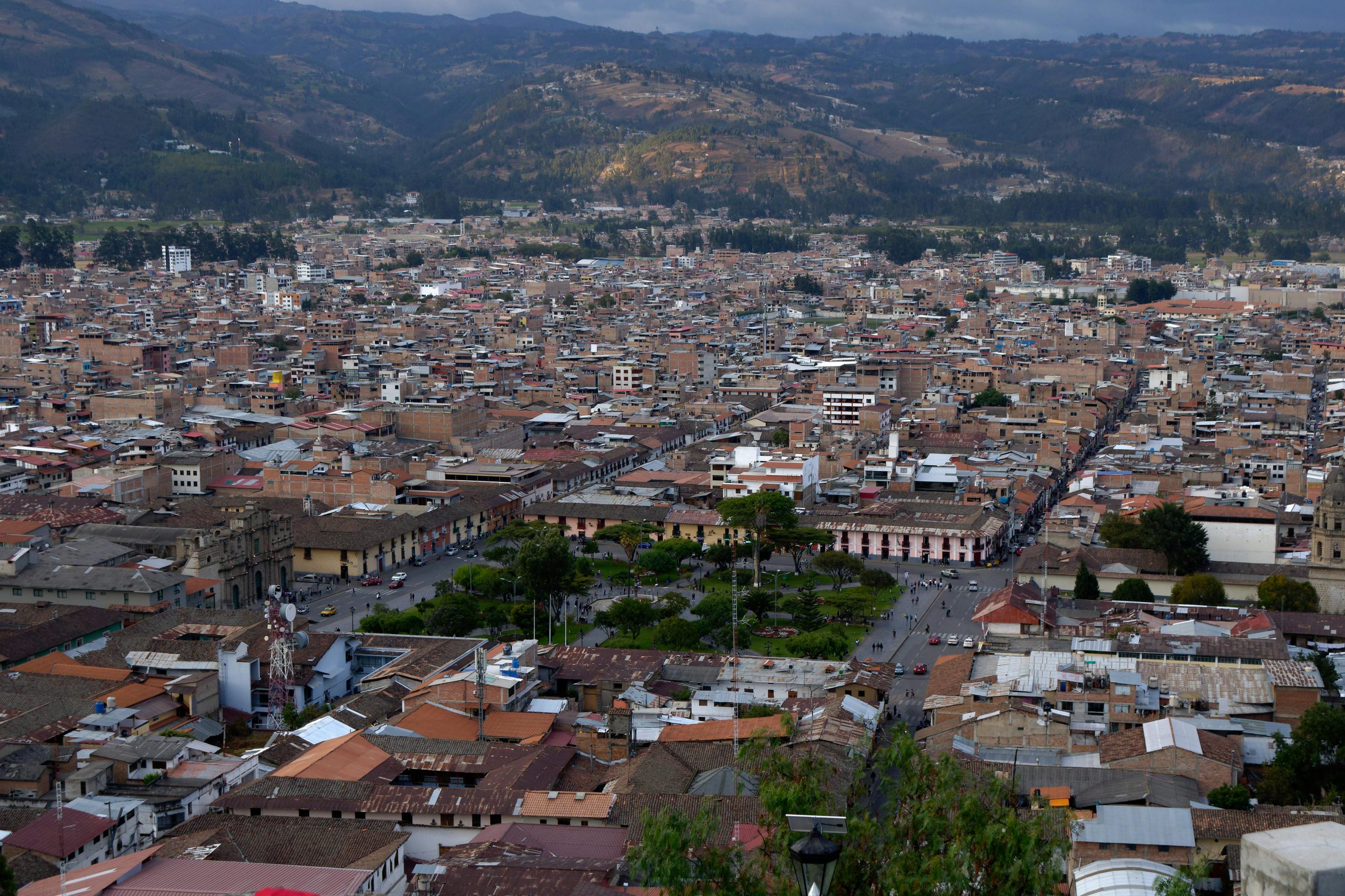 Panoramic view of Cajamarca, Peru, showing the city's colonial architecture, the central plaza, and surrounding mountains.