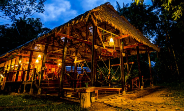 Rustic Amazon lodge lit up at night in the rainforest
