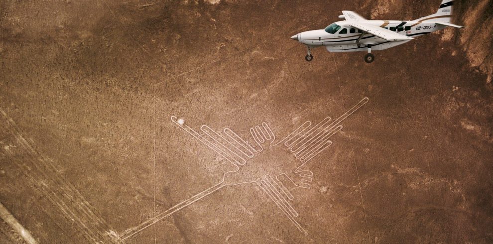 A small airplane flying over the ancient Nazca Lines geoglyphs in the desert.